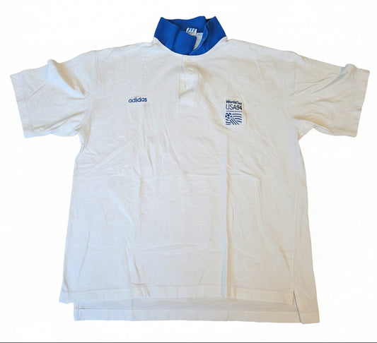White Adidas FIFA World Cup USA 94 golf polo with royal blue collar, embroidered Adidas wordmark and World Cup USA 94 crest on chest, size XL